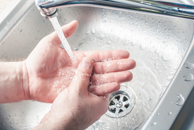 male washing hands under water